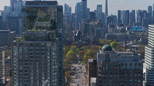 Urban landscape showcasing Toronto's modern skyscrapers, downtown core, Queen's Park with cars driving on University Avenue and Wellesley Street during daytime