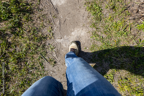 A person's legs and a foot walking on a trail looking from above.