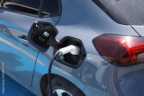 Electric Car Charging with White Plug in Blue Vehicle Port