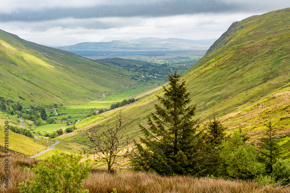 Obraz premium Glengesh Pass winding through a green mountain valley in County Donegal, Ireland. A scenic road landscape of the Wild Atlantic Way and remote Irish highlands.
