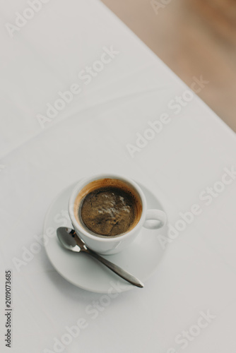 Cup of black coffee on a white table in a street cafe. Flat lay. Place for text.