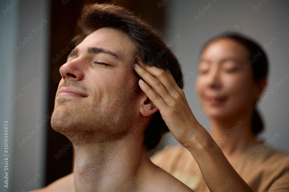 Fototapeta premium Smiling man receiving head massage at wellness spa.