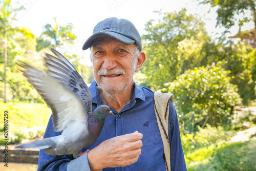 Colombian old man holds a dove flying in his hand showing it to the camera