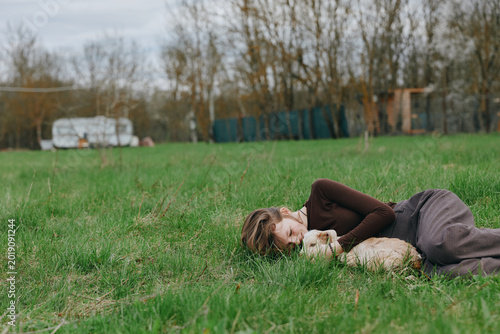 Billede på lærred A relaxed woman lies beside a playful goat kid in a bright grassy field