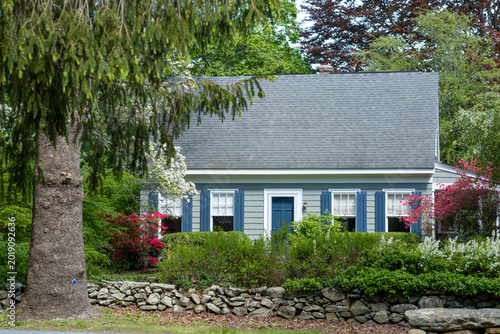 Charming cottage house with spring flowers and stone wall.