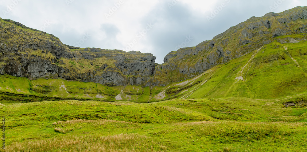 Obraz premium Gleniff Horseshoe in County Sligo, Ireland, with rolling grassland beneath steep limestone mountains and bright clouds. A scenic drive through one of Irelands classic valleys.