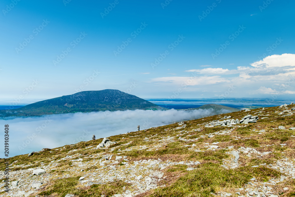Fototapeta premium Mountain view from Minaun Heights on Achill Island, County Mayo, Ireland. Scenic rocky summit landscape above clouds, coast and Atlantic islands.