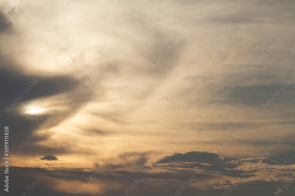 Fototapeta premium Elegant cloud textures illuminated by fading sunlight over a calm evening horizon, creating a peaceful atmospheric sky background with warm neutral tones.
