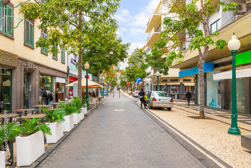 The pedestrianized Rua Fernao de Ornelas main street of colorful shops and sidewalk cafes in the historic downtown of Funchal Portugal, Madeira Island.