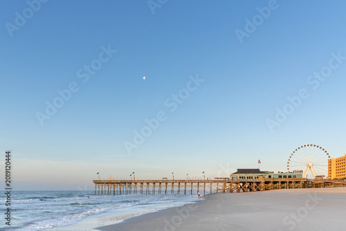 Moon setting, looking south down Myrtle Beach to the pier and boardwalk in the early morning light