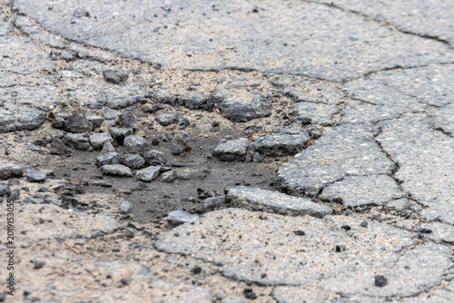 Принти на полотні La Tuque, Canada, 01 May 2026 : Close-up view of a damaged asphalt road surface with cracks, loose gravel, and a pothole