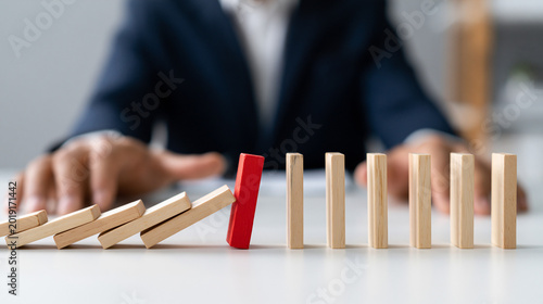 Domino Effect: A decisive red domino stands out, halting the cascading fall of wooden dominoes, symbolizing a pivotal moment of control. 