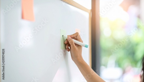 Close-up of a hand writing on a whiteboard with a marker pen, natural light