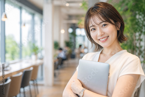 Fototapeta カフェでノートPCを持つ笑顔の若い女性