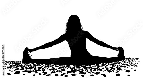 Silhouette of woman doing seated wide leg stretch on pebbled ground