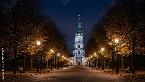 Nighttime city street with church tower.