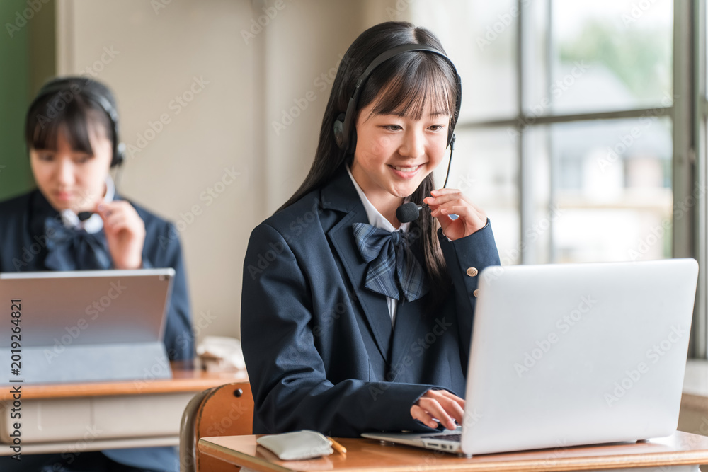 Fototapeta premium Elementary, middle, and high school girls in school uniforms using computers for lessons.