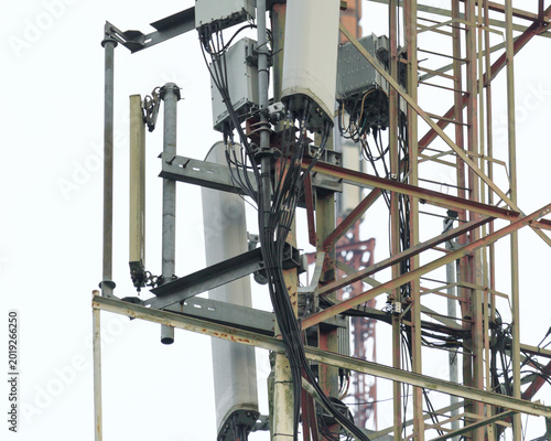 Closeup cellular tower infrastructure with sector panel antenna, remote radio unit, feeder cable, mounting bracket and lattice mast telecommunication equipment isolated background