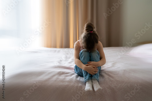 Tableau sur toile A little sad girl sitting on a bed with motion blur effect