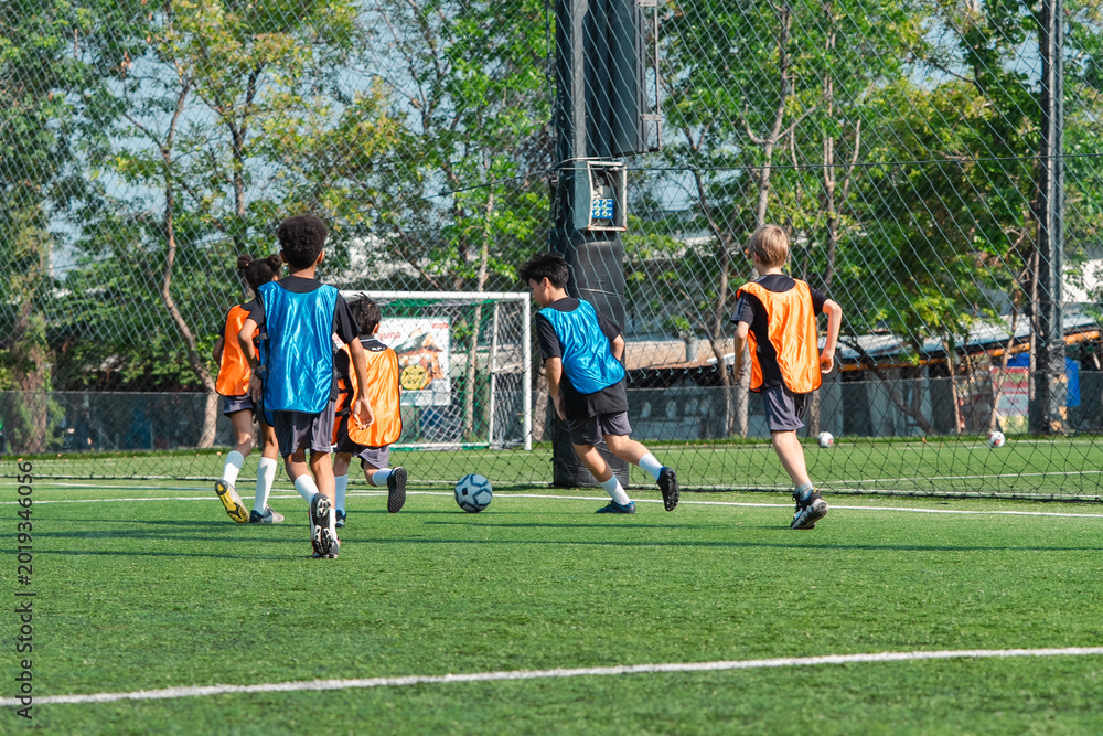 Fototapeta premium World cup concept with soccer ball or football player, youth soccer players on green field training near goal net in outdoor sports practice session