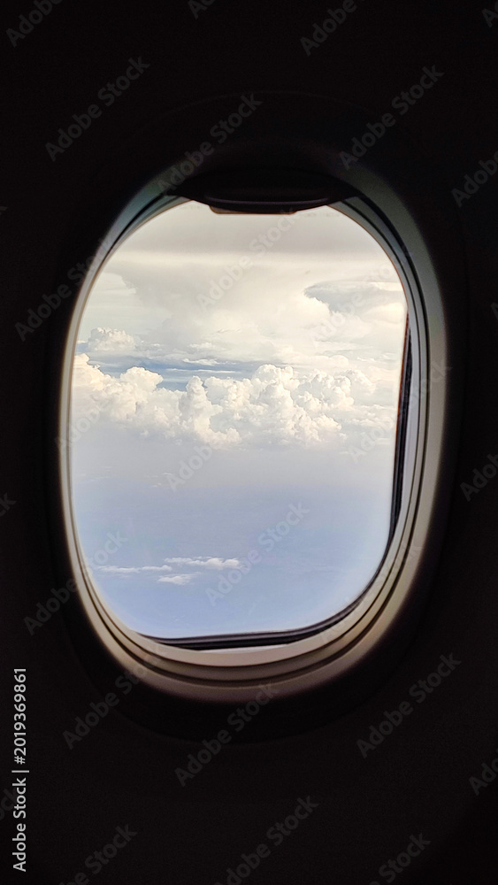 Fototapeta premium Cloud View from Airplane Window Above the Sky During Flight