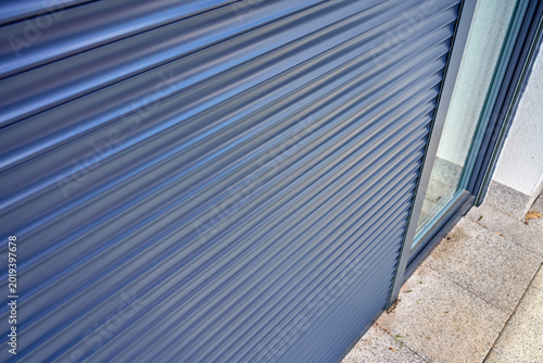 Closed roller shutter on glass door outside modern home