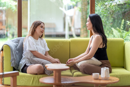 Two Female Friends Talking Face to Face on Sofa at Home