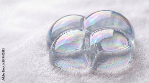 Macro close-up of iridescent soap bubbles on soft white fabric, skincare and beauty concept