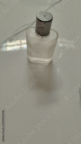 Frosted Glass Perfume Bottle with Silver Cap on White Marble Background