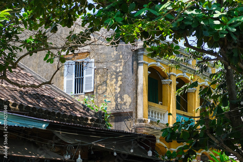 Foto Historic yellow colonial building surrounded by tropical trees in Hoi An Vietnam