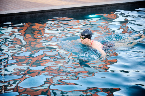 Woman swimming breaststroke in outdoor pool. Concept of fitness, wellness and active lifestyle, endurance training, healthy habits, relaxation and recreation in water