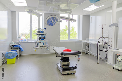 Foto Modern empty operating room with surgical equipment and medical bed