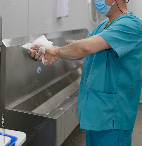 Surgeon drying hands with paper towel after washing in hospital