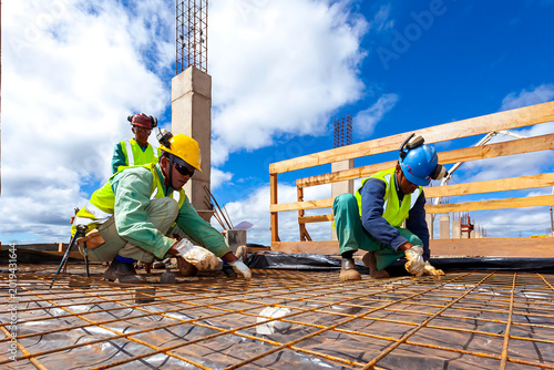 Construction workers installing steel reinforcement mesh on building site