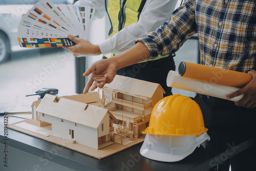Construction worker assembling architectural model with tools on table