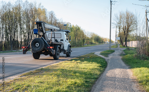 Photos Heavy crane truck with specialized equipment driving away down an asphalt road,