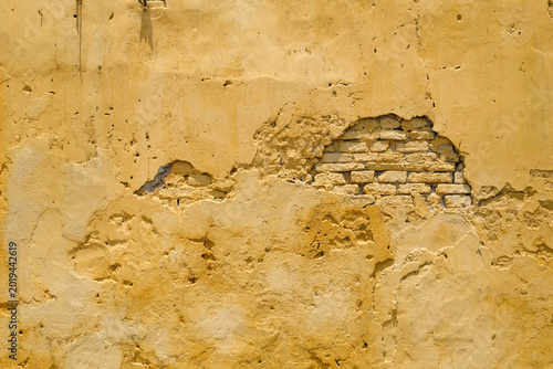 Foto Weathered yellow wall texture with exposed brick in Hoi An Vietnam