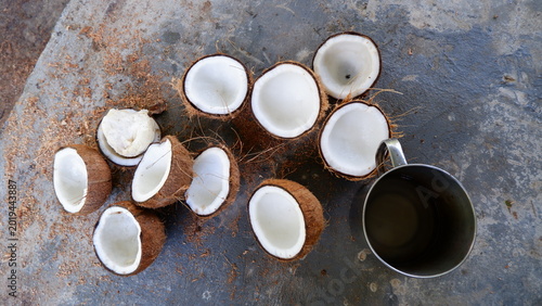 Canvas Print a high-angle shot capturing several halved mature coconuts displaying thick white coconut flesh arranged on a rustic grey surface with coconut fibers