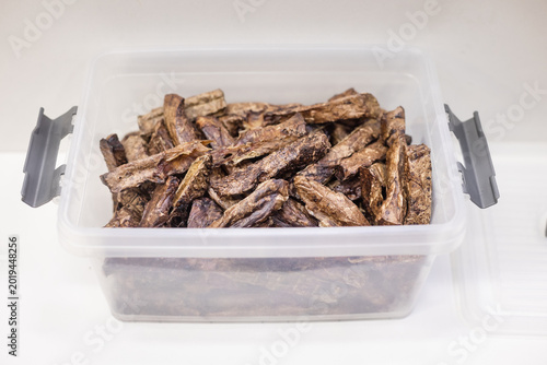 Container filled with dried treats for pets. Fish treats, storage box, pet snack, dried, store stock