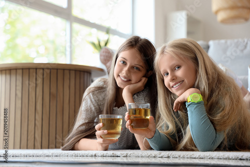 Little girls with glasses of juice at home