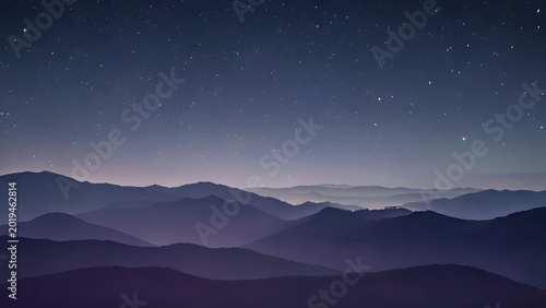 Distant purple mountain ranges under a starry night sky with soft hazy atmosphere