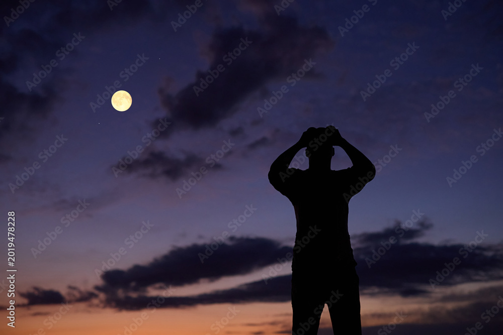 Fototapeta premium Amateur astronomer using binoculars for observing stars, planets, Moon and other celestial objects.
