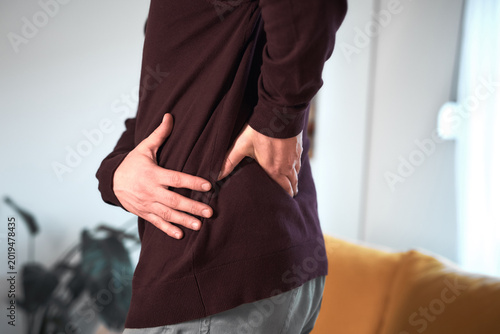 Man with hip, back, spine and sciatica pain at home.