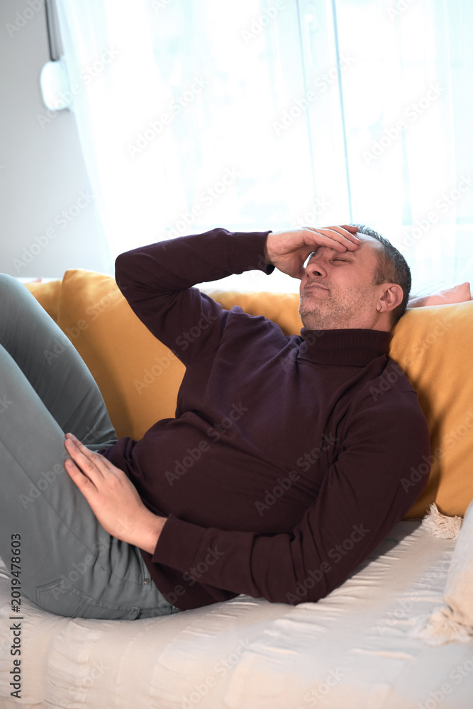 Fototapeta premium Man with headache, depression, sadness and loneliness at home.