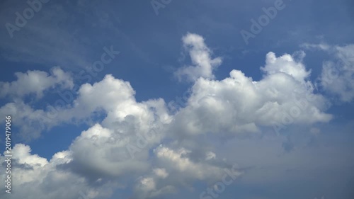Horizontal movement of white clouds across a blue sky on a sunny day