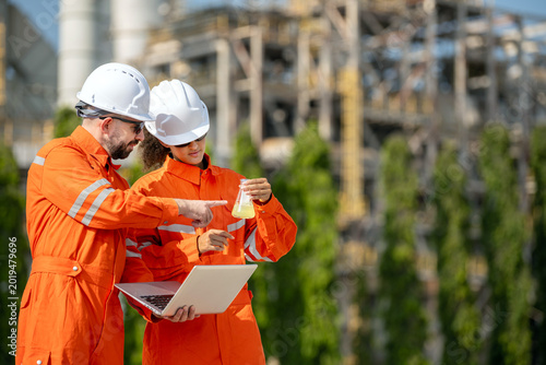 Tableau sur toile Petroleum chemist and laboratory technician analyzing fuel sample quality test with flask and laptop while discussing octane and cetane values chemical testing at oil refinery industrial site