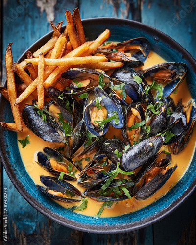 Traditional moules frites dish featuring steamed mussels in cream sauce and golden french fries