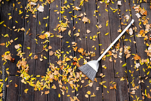 Bild auf Leinwand autumn cleaning background with a plastic broom and fallen leaves