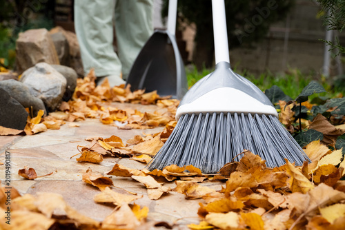 Photos Plastic broom sweeping autumn leaves, outdoor cleaning in the garden