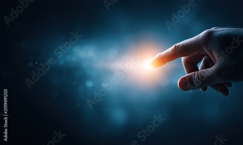 Human finger pointing to glowing light against dark, bokeh background